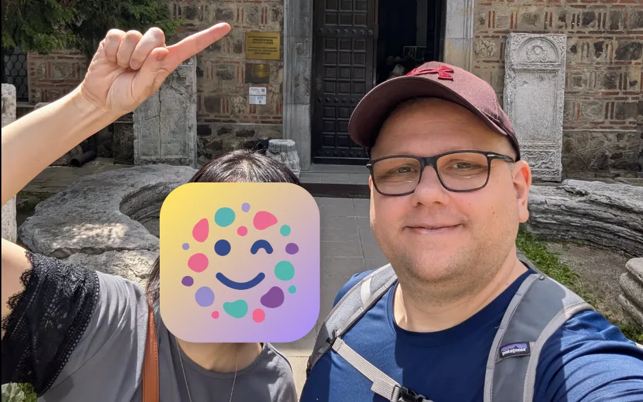 Wolfi's wife pointing up in front of a museum, face covered by a littledots icon, with Wolfi smiling beside